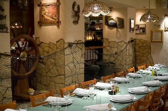 Unutrašnjost konobe — prostorija s kamenim zidom i kockastim stolnjacima